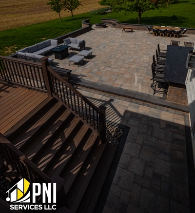 Paver steps and railing on brick wall. Entrance with gray paver steps, metal railing, and brick wall, with greenery in the background.